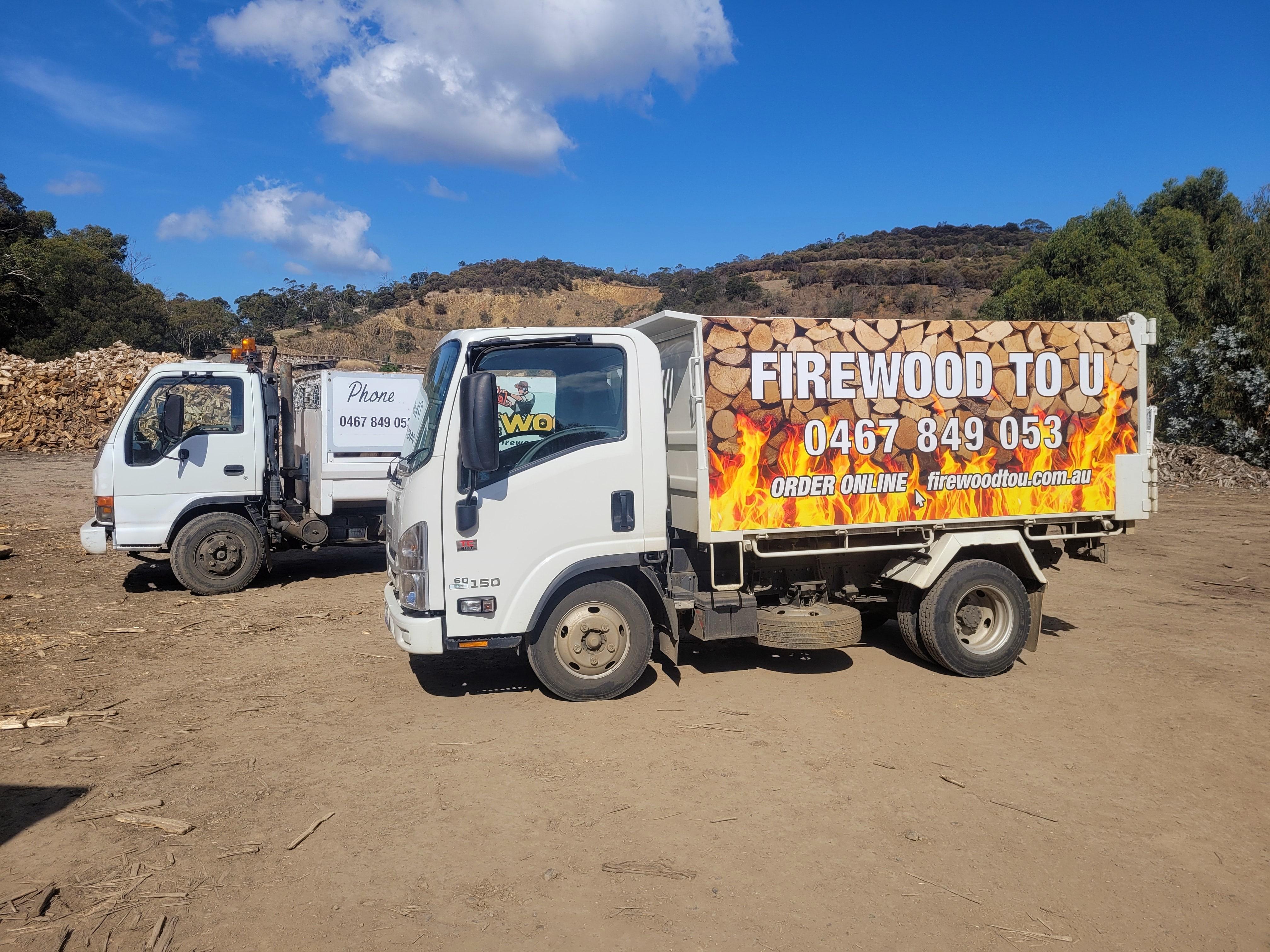 Photo of two delivery trucks loaded with firewood